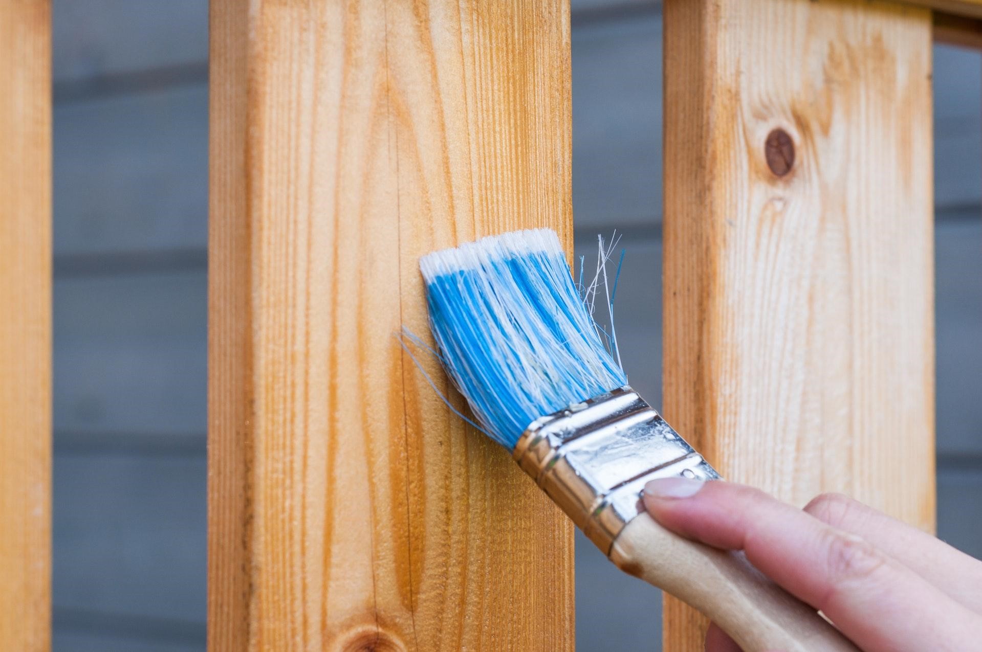 05_RueBaRue_Rental Management_Photo of someone using a paintbrush to maintain wooden balcony